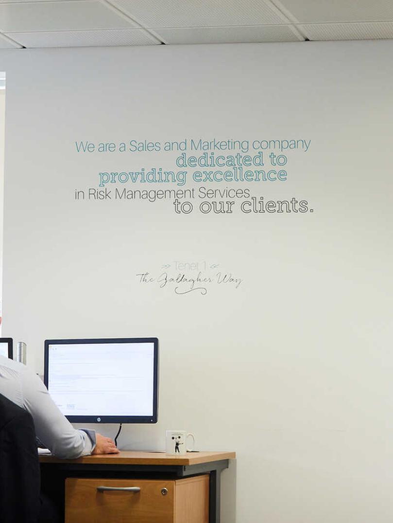 Man working in an office with slogan written on the wall above