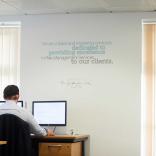 Man working in an office with slogan written on the wall above